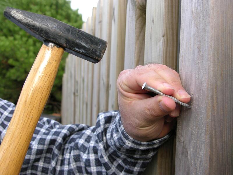 worker hammering fence